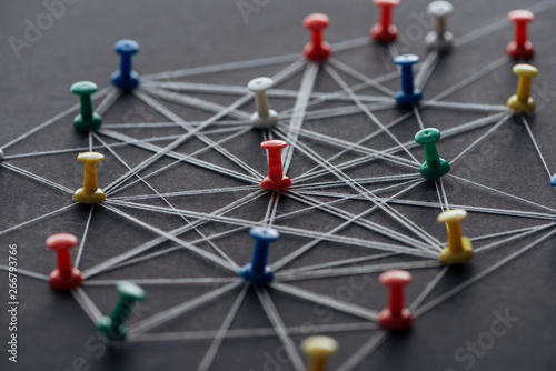 selective focus of push pins connected with strings isolated on grey, network concept