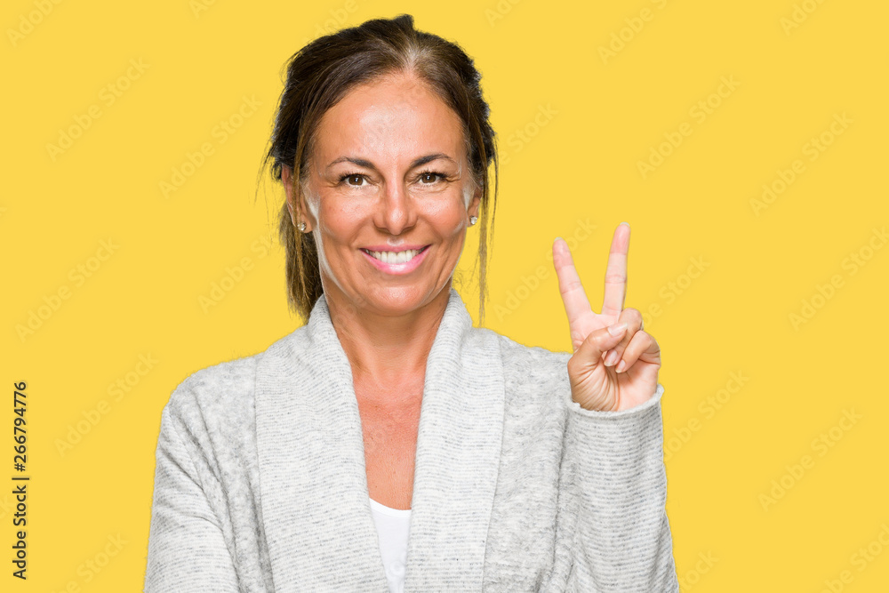 Beautiful middle age adult woman wearing winter sweater over isolated background smiling with happy face winking at the camera doing victory sign. Number two. Beautiful middle age adult woman wearing winter sweater over isolated background smiling with happy face winking at the camera doing victory sign. Number two.