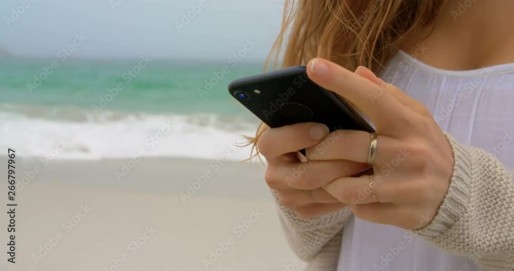 Mid section of woman using mobile phone on the beach 4k