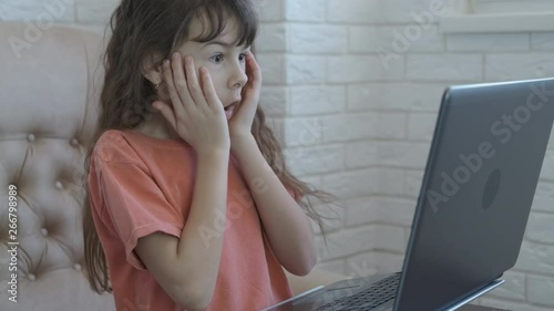 Shock on the Internet. A child on the Internet without parental control. The little girl is shocked by what he saw in the laptop coiner. photo