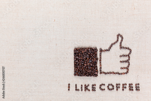 Thumbs up with 'I like coffee' made from coffee beans on linen texture, arranged bottom right.