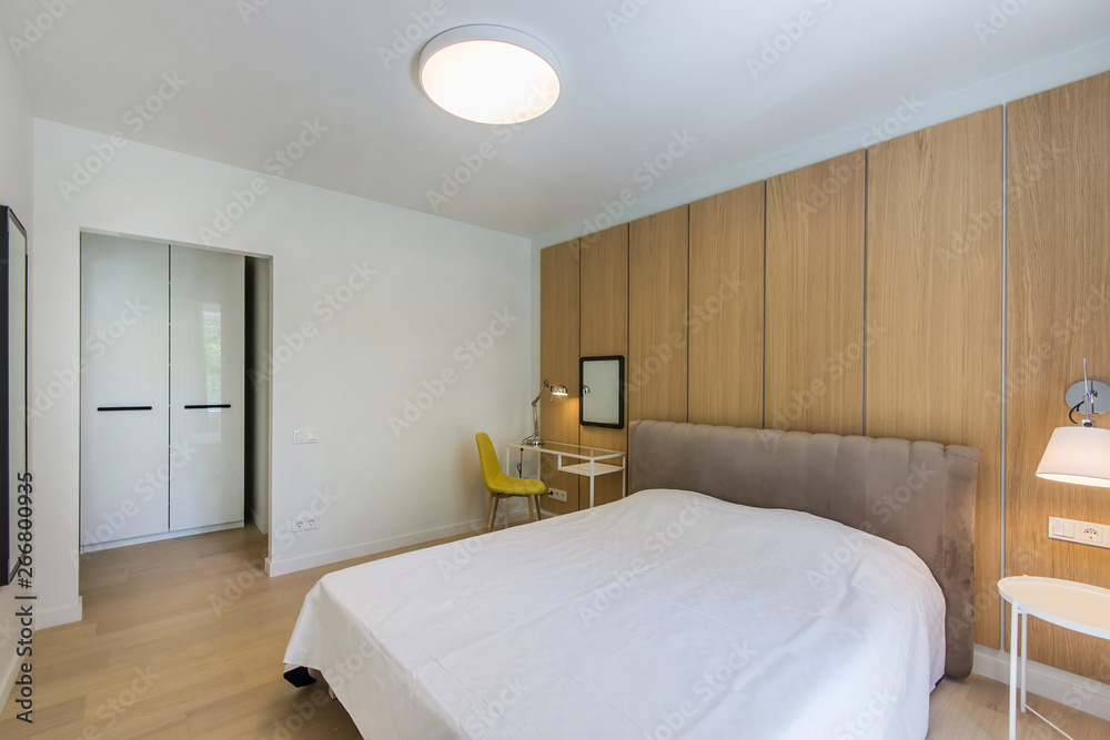 Fototapeta premium Simple bedroom interior with double bed, nightstand, small glass table , white bedding and wardrobe