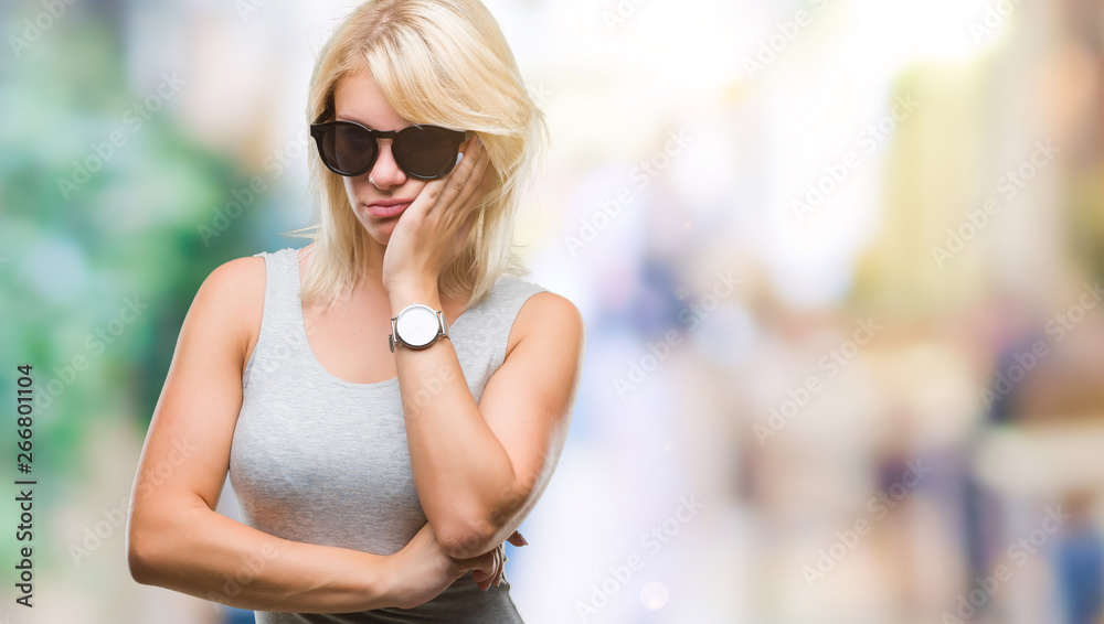 Young beautiful blonde woman wearing sunglasses over isolated background thinking looking tired and bored with depression problems with crossed arms.