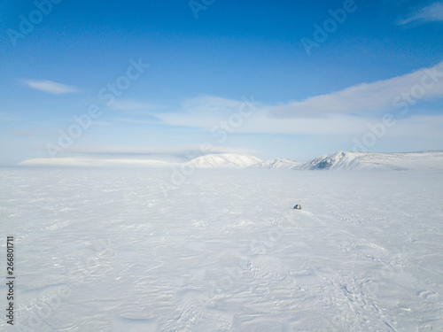 The car rides through the snow-covered Arctic Ocean. Aerial photography