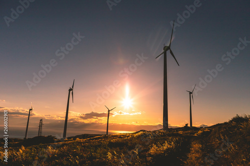 Silhouette al tramonto di un impianto eolico, fonte di energia elettrica verde rinnovabile su una collina vicino al mare. Concetto di ecologia.