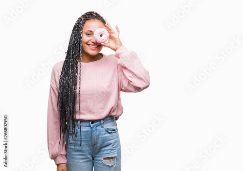 Young african american girl eating pink donut over isolated background with a happy face standing and smiling with a confident smile showing teeth © Krakenimages.com