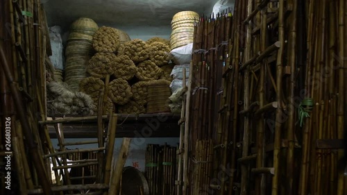 Handmade items ready to be sold in a marketplace or bazaar.  Bamboo ladders, weaved baskets and handmade ropes to sell. Handheld. 