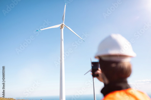 Ingegnere sta fotografando l'impianto eolico, composto da una turbina movimentata dal vento. Concetto di fonte rinnovabile e manutenzione.