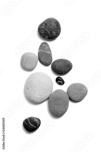 Rozproszone kamyki morskie. Gładkie szare i czarne kamienie na białym tle. Widok z góry