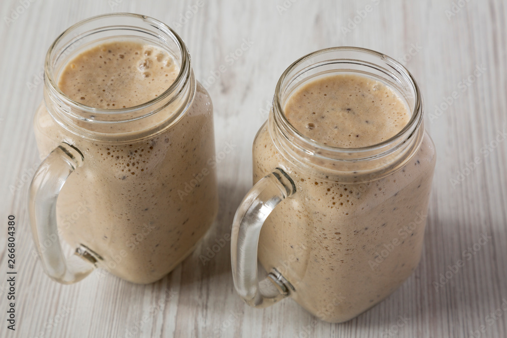 Banana, kiwi, apple smoothie with chia seeds in glass jars, low angle view. Close-up. Banana, kiwi, apple smoothie with chia seeds in glass jars, low angle view. Close-up.