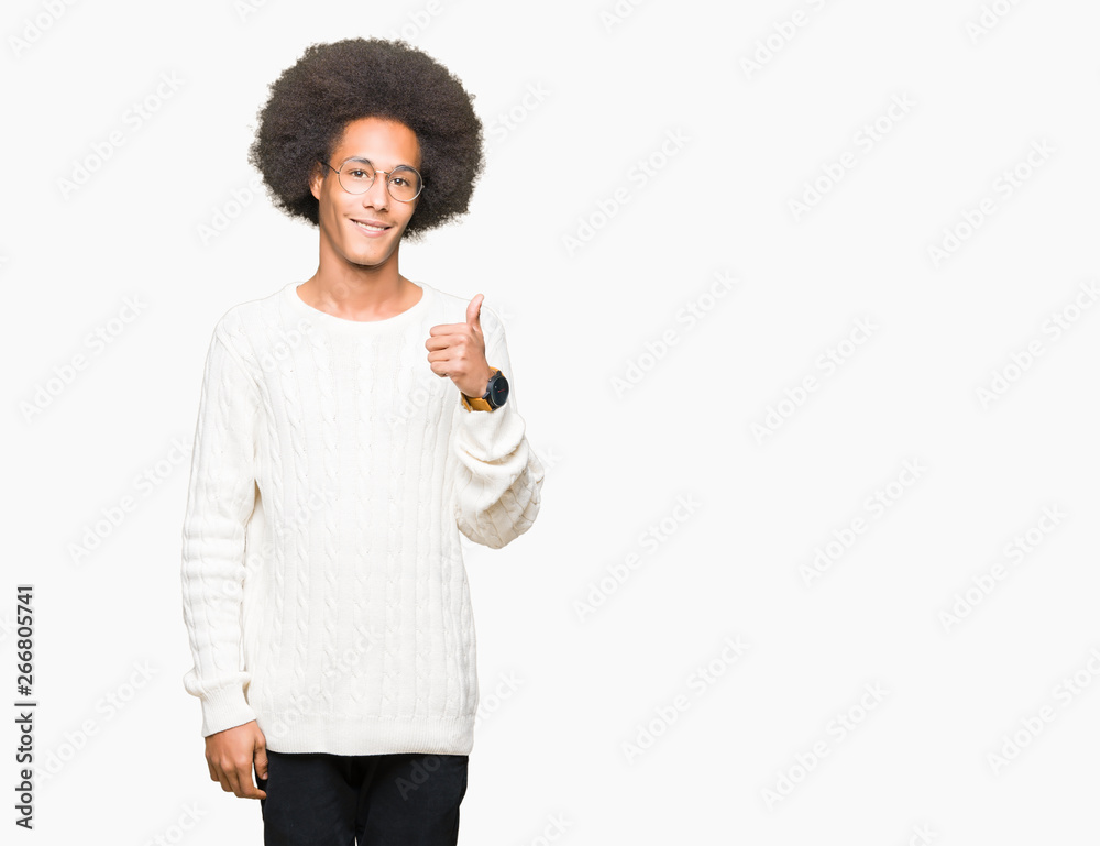 Young african american man with afro hair wearing glasses doing happy thumbs up gesture with hand. Approving expression looking at the camera with showing success. Young african american man with afro hair wearing glasses doing happy thumbs up gesture with hand. Approving expression looking at the camera with showing success.