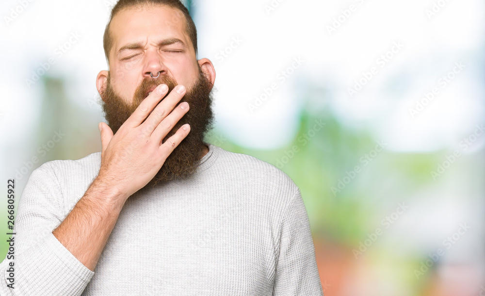 Naklejka premium Young blond man wearing casual sweater bored yawning tired covering mouth with hand. Restless and sleepiness.