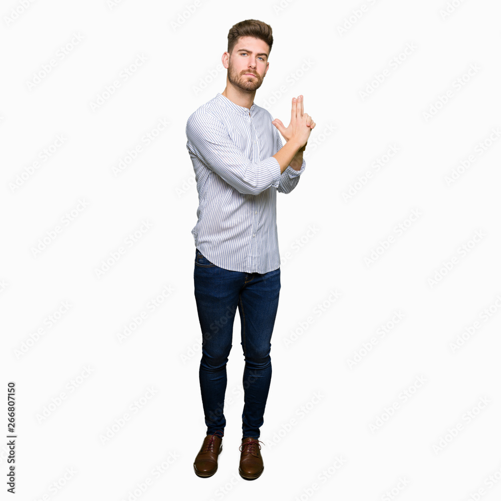 Young handsome man Holding symbolic gun with hand gesture, playing killing shooting weapons, angry face Young handsome man Holding symbolic gun with hand gesture, playing killing shooting weapons, angry face