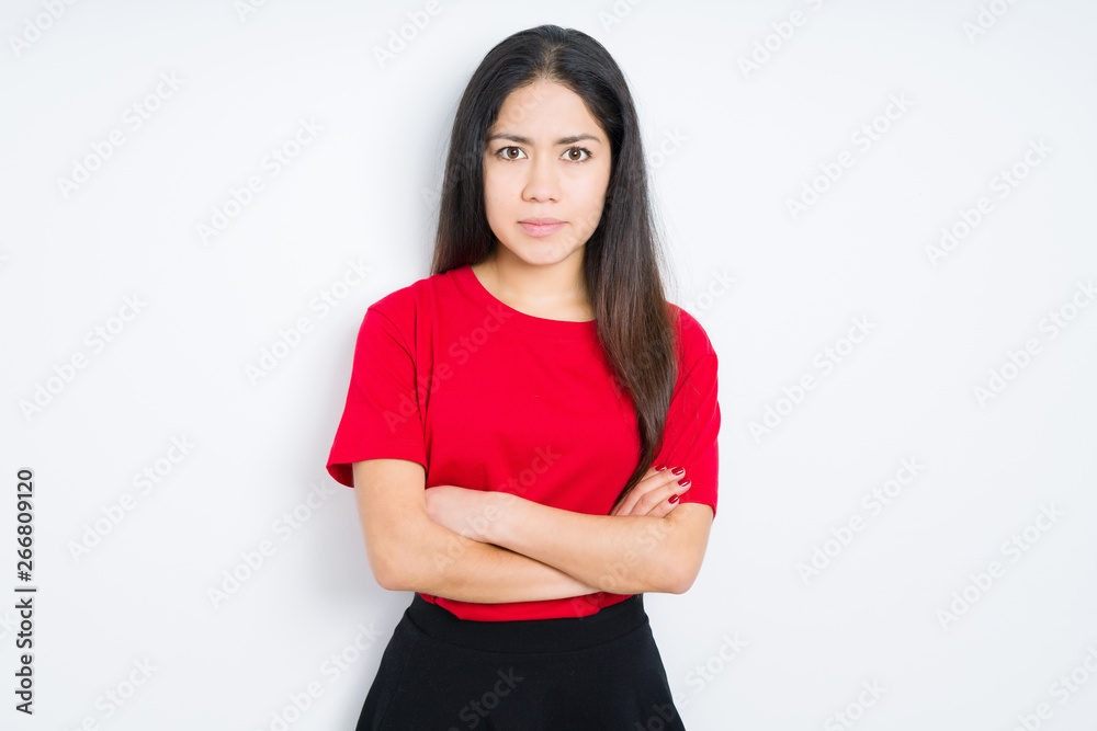 Beautiful brunette woman wearing red t-shirt over isolated background skeptic and nervous, disapproving expression on face with crossed arms. Negative person. Beautiful brunette woman wearing red t-shirt over isolated background skeptic and nervous, disapproving expression on face with crossed arms. Negative person.
