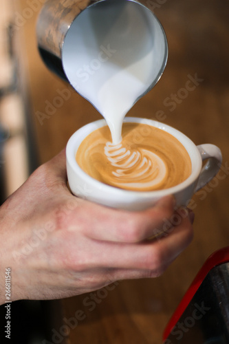 barista man preparing coffee (cappuccino), pouring milk