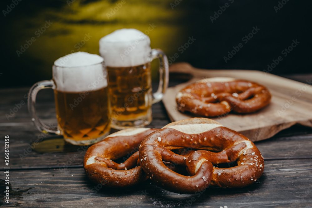 tasty pretzels on dark wooden background with draft beer in the mug in blurred background tasty pretzels on dark wooden background with draft beer in the mug in blurred background