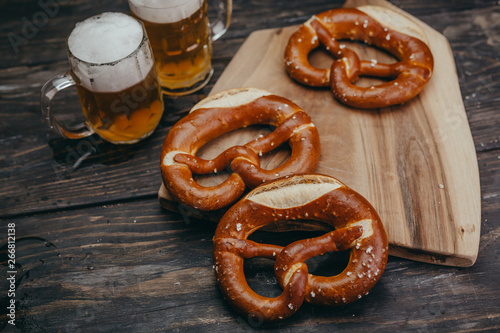 overhead view of pretzels and draft beer in the mug on wooden dark table