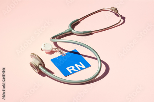 Registered Nurse ID Badge and Stethoscope on Pink Background 