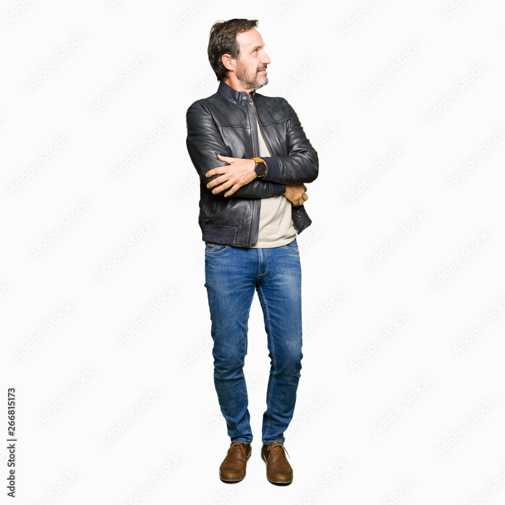 Fototapeta premium Middle age handsome man wearing black leather jacket smiling looking to the side with arms crossed convinced and confident