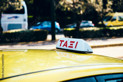 Taxi sign on a yellow cab in central Athens, Greece with defocused cars in background