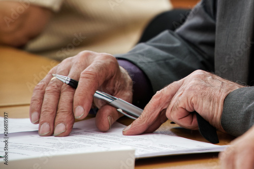 An elderly man writes a pen in the questionnaire. Old age and learning. Unemployment and retirement