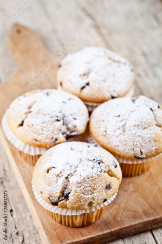 Homemade fresh muffins with sugar powder on cutting board rustic wooden table.