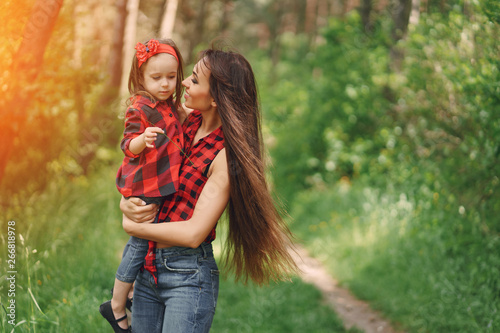 Young and very beautiful slim mum with long hair walking in a sunny summer park with her little beauties daughter © prostooleh