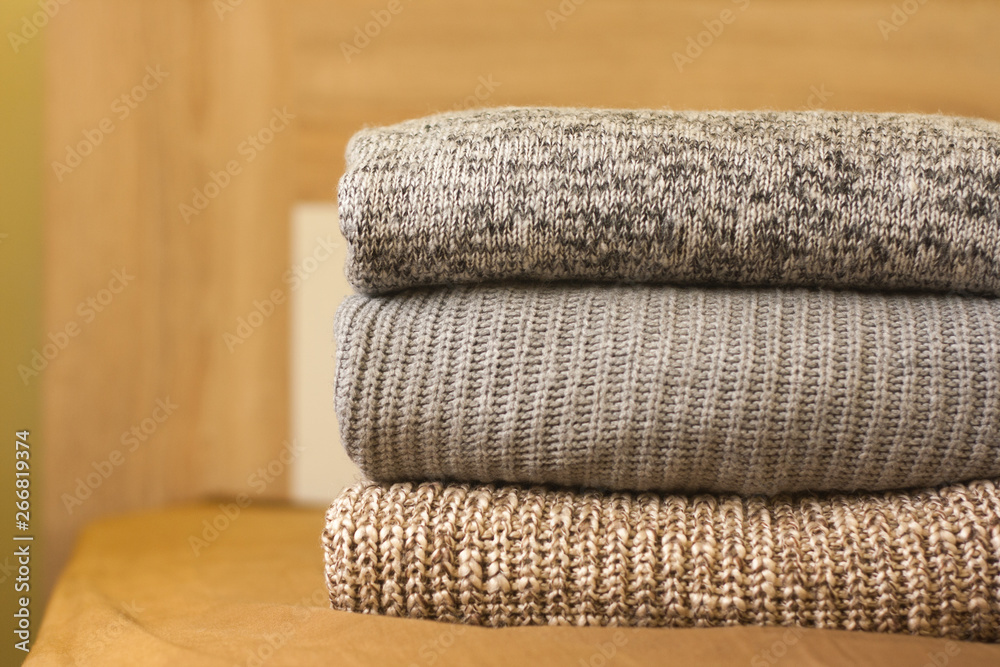 A pile of warm sweaters on the wood bed