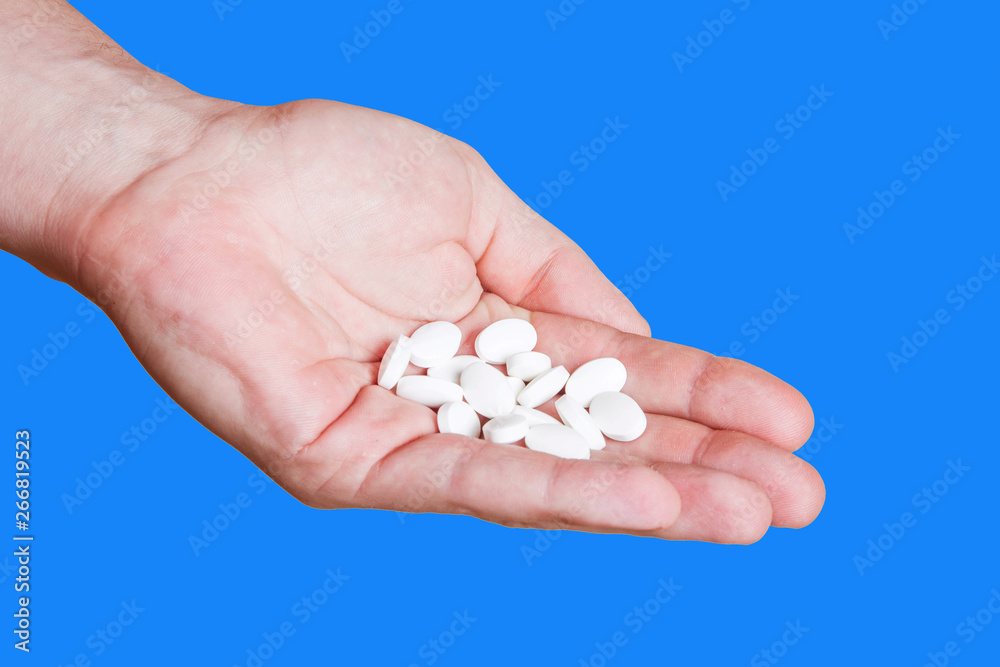White pills on hand isolated on blue background. White pills on hand isolated on blue background.