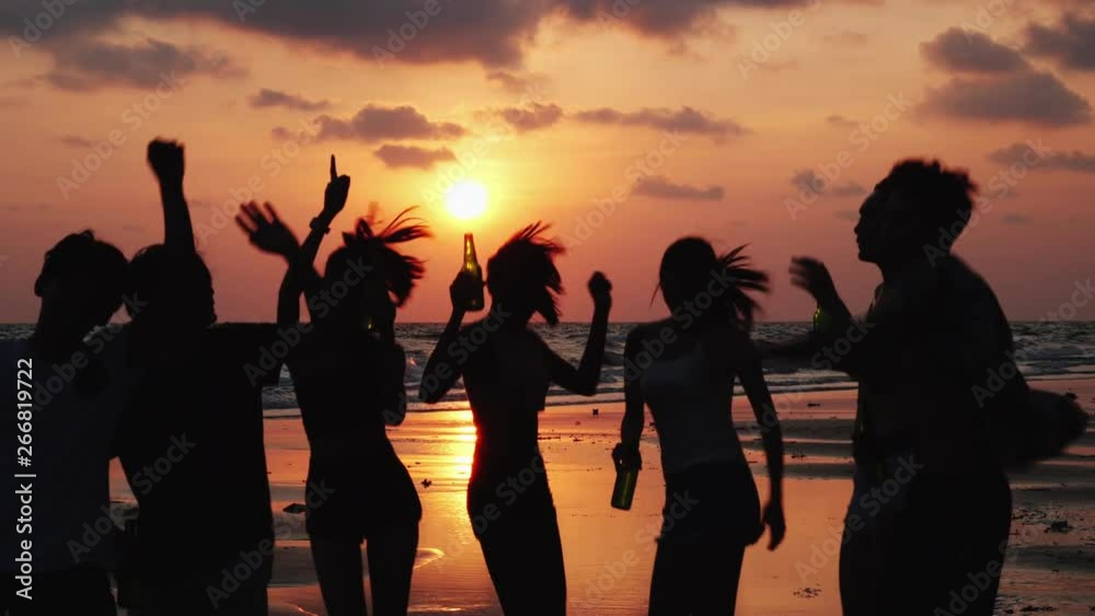 Silhouette of Asian teen group dancing and drinking beverage together in beach summer with sunset background. Young asia happy emotion and anniversary celebration. 4K resolution and slow motion.