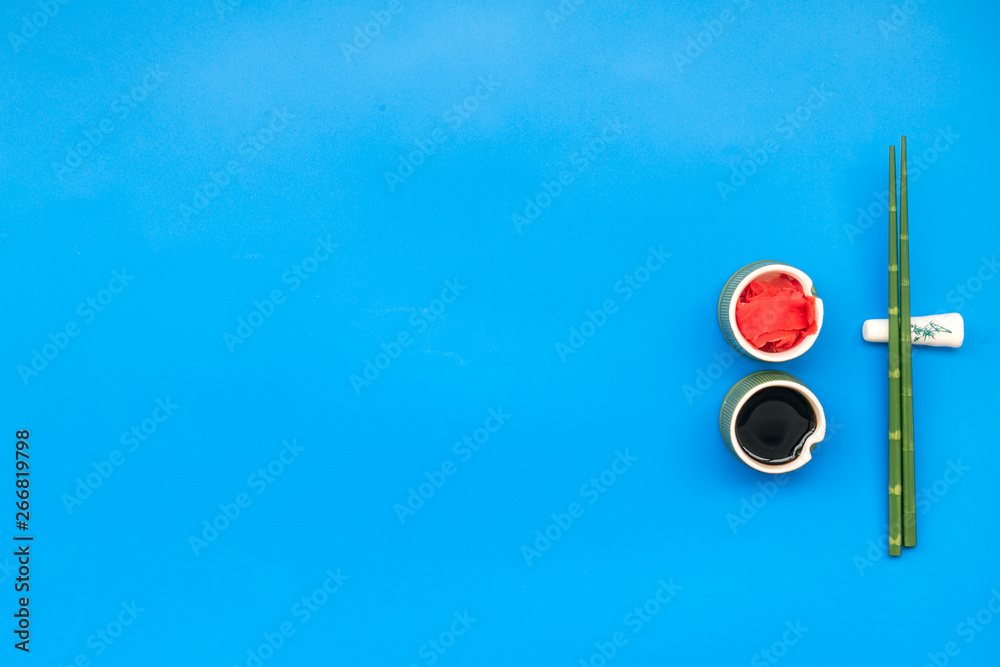 oriental table set up with bamboo sticks for sushi and maki, soy sauce on blue background top view space for text oriental table set up with bamboo sticks for sushi and maki, soy sauce on blue background top view space for text