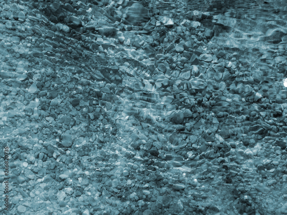 blue pebbles and ripples on running water with light reflected on the surface blue pebbles and ripples on running water with light reflected on the surface