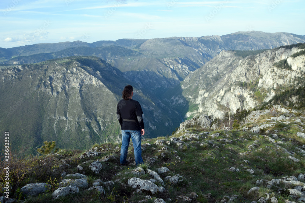 Young man stands in the edge of Tara Canyon and Tara River - Durmitor National Park. Near Zabljak, Montenegro.