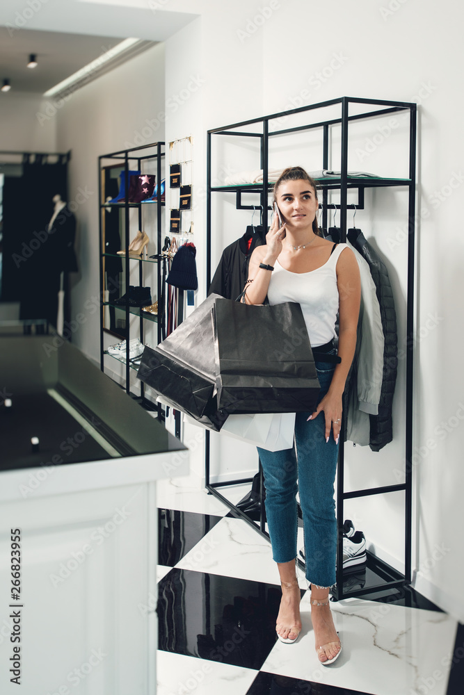 Smiling girl doing many purchases at the clothing shop. Woman with packeges in hands in a clothing boutique Smiling girl doing many purchases at the clothing shop. Woman with packeges in hands in a clothing boutique