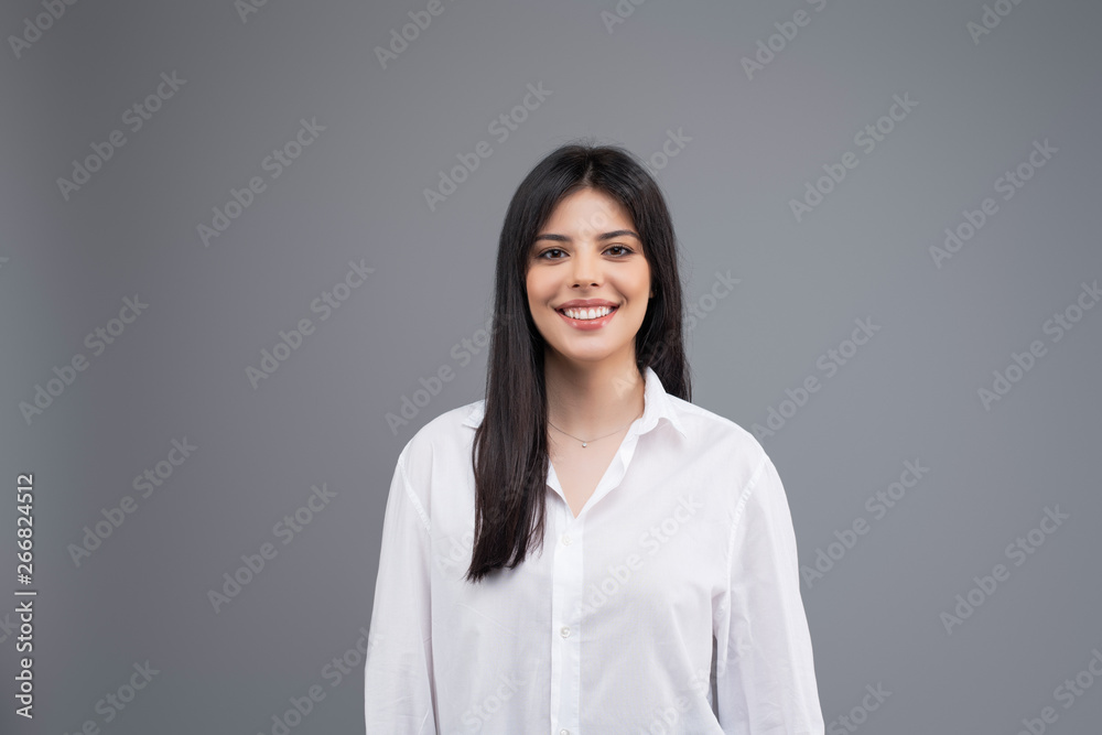 Portrait of a smiling young business woman in white shirt isolated over grey background Portrait of a smiling young business woman in white shirt isolated over grey background