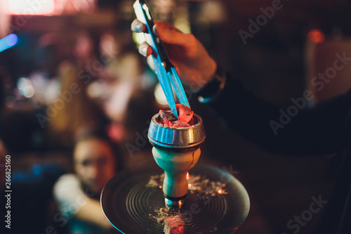 the guy changing the coals on the hookah in the hookah atmospheric.