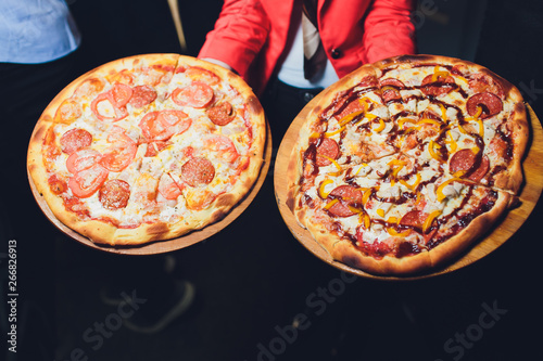 Waiter carrying two different plates with a tasty pizza. Photo with two pizza. Pizza with mushrooms and pizza with salami. Italian food. Italian restaurant. photo