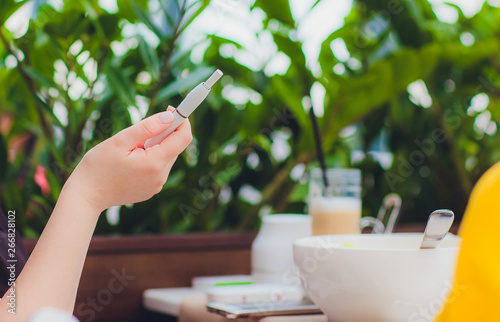 heat-not-burn tobacco product technology. woman holding e-cigarette in his hand before smoking. photo