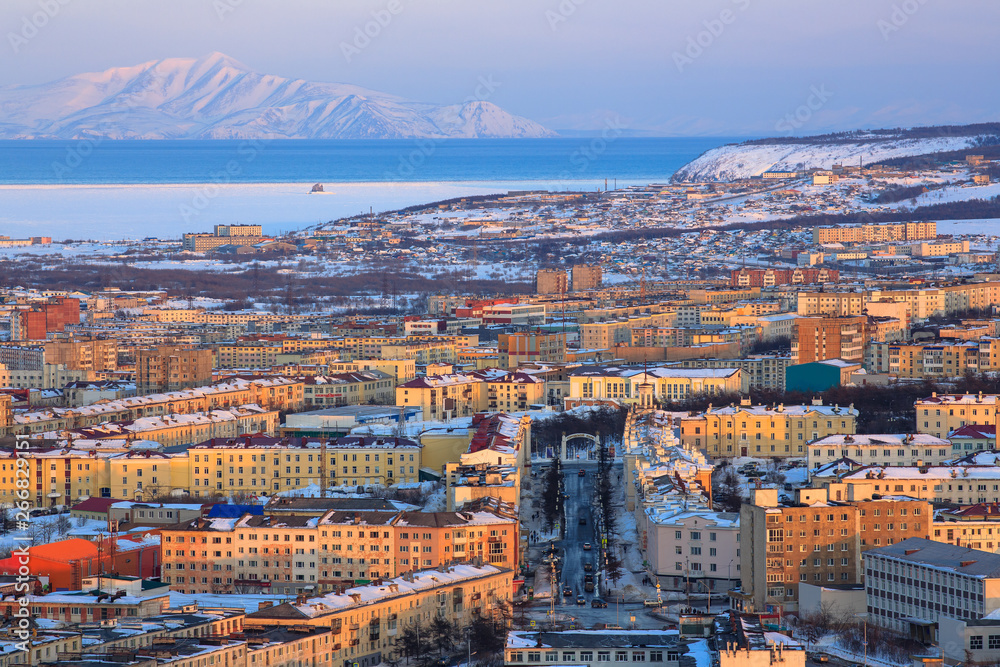 Aerial view of the city of Magadan. Beautiful landscape with city, sea bay and mountains. Evening cityscape. Magadan is the administrative center of the Magadan Region, Russia. Siberia. Far East.