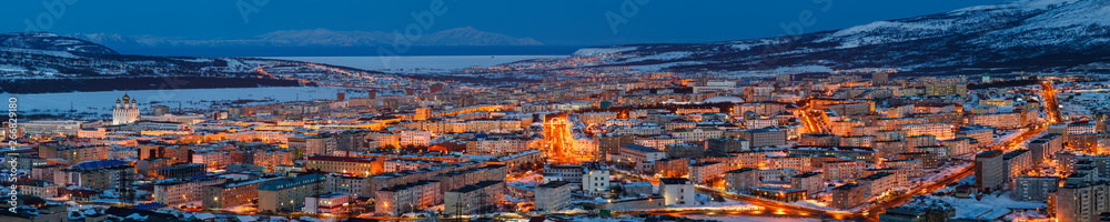 Panorama of the city of Magadan. Top view of the northern city. Beautiful night cityscape with lots of buildings. Bright street lighting at dusk. Magadan, Siberia, Far East of Russia. Panoramic photo.