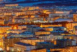 Aerial view of the night city. Cityscape with many buildings. Top view of the town with bright street lighting at dusk. City of Magadan, Siberia, Far East of Russia.