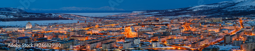 Panorama of the city of Magadan. Top view of the northern city. Beautiful night cityscape with lots of buildings. Bright street lighting at dusk. Magadan, Siberia, Far East of Russia. Panoramic photo.
