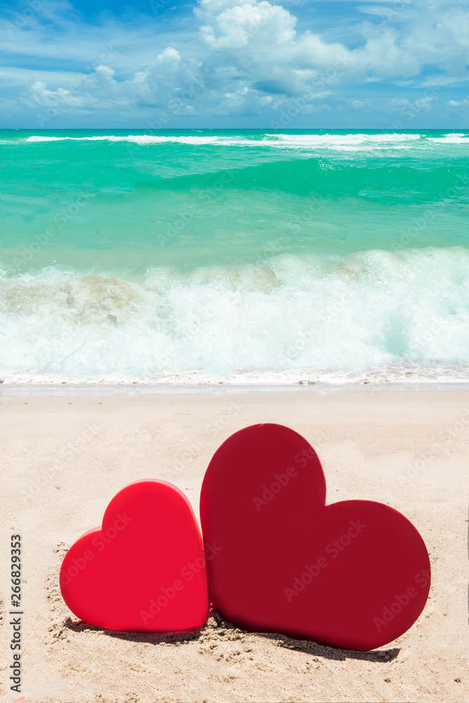 Fototapeta premium Two hearts on the sandy beach background