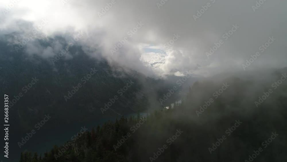 Flying drone to the lake through a cloud over a mountain with cedars Flying drone to the lake through a cloud over a mountain with cedars