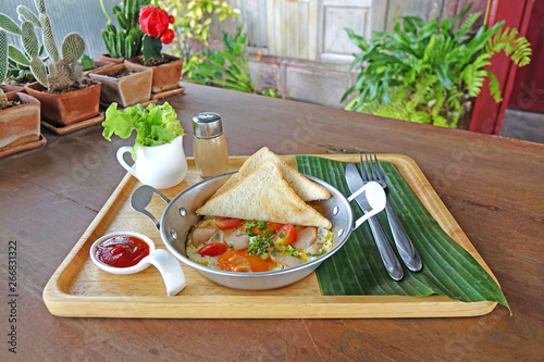 Indochina Omlette, sunny side up topping with Chinese sausage, ground pork, tomato and spring onions served with bread, vegetables and tomato sauce. Thai style breakfast. Indochina pan-fried egg. photo