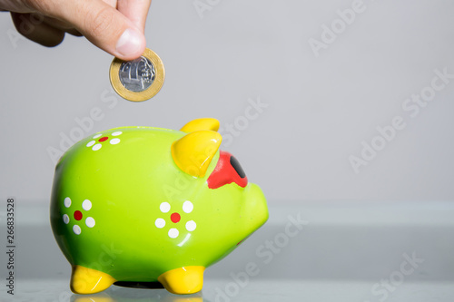 Colocando moedas no cofre de porquinho, economizar dinheiro na poupança photo