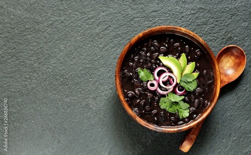 thick black bean soup or stew. Latin American or Mexican cuisine. stewed black beans served with avocado and red onion and cilantro. place for text. top view. photo