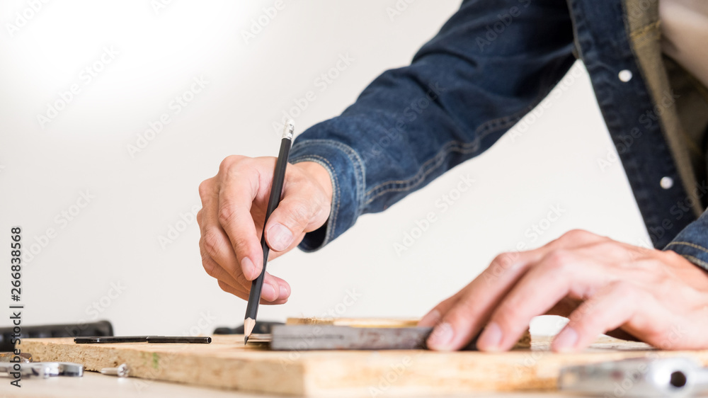 Carpenter working carefully looking at the plans work in carpentry. He is successful entrepreneur at his workplace. hammering a nail Supports On Building Site work with cutter. Carpenter working carefully looking at the plans work in carpentry. He is successful entrepreneur at his workplace. hammering a nail Supports On Building Site work with cutter.
