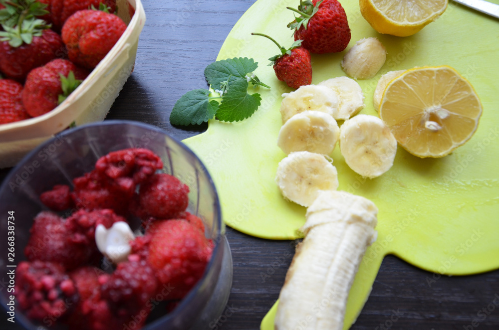 Strawberry and banana smoothie in the jar. Ingredients for making smoothies strawberry banana, frozen berries in a blender on a dark black wooden background. Strawberry and banana smoothie in the jar. Ingredients for making smoothies strawberry banana, frozen berries in a blender on a dark black wooden background.