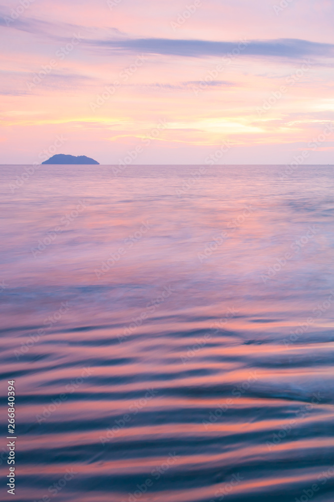 Obraz premium A tranquil beach and ocean waves at sunset.
